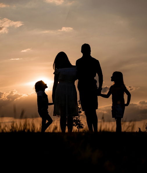 a family standing in a field at sunset